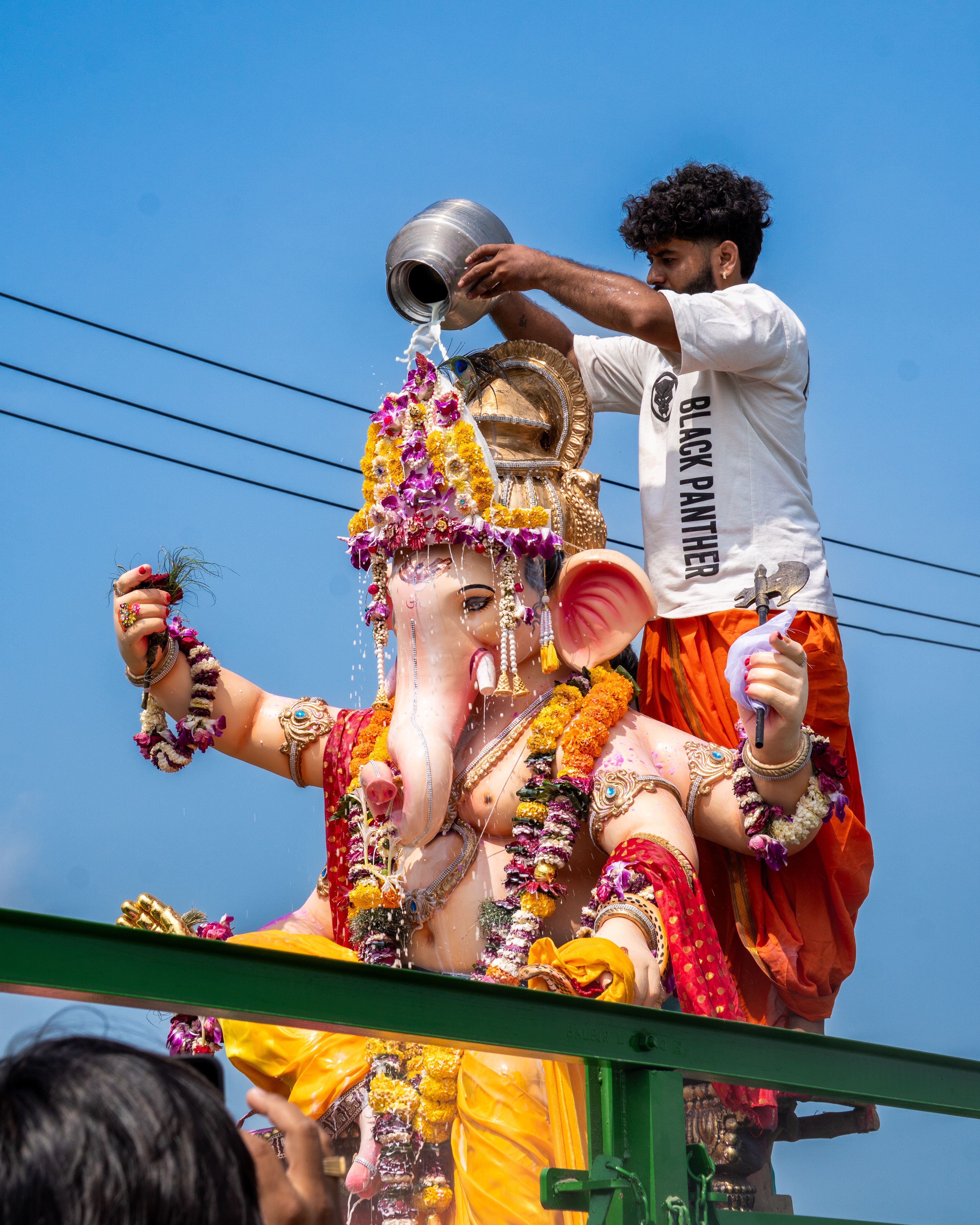 A man performs a Ganesh idol water ritual during a vibrant festival in Surat, India.