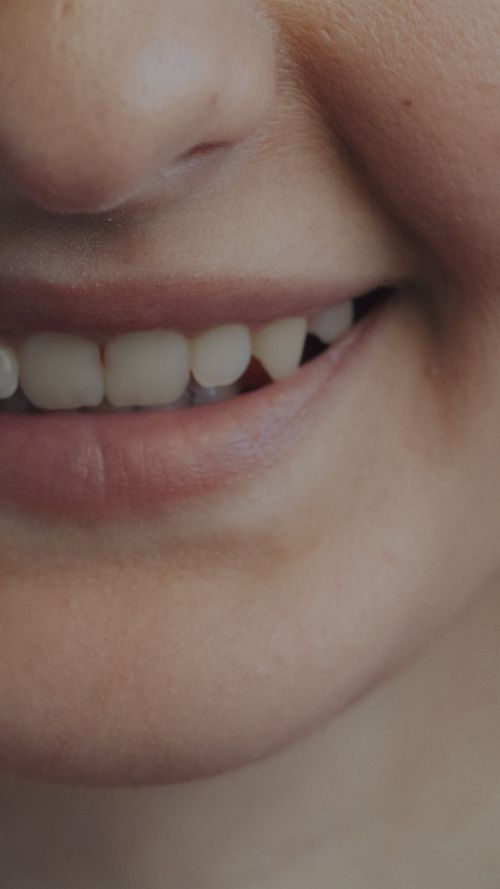Free A detailed close-up of a person's smiling mouth showcasing clean teeth and healthy skin. Stock Photo