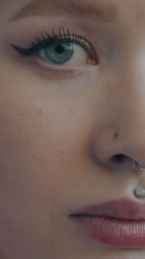 Free Close-up of a woman's face with piercings, showcasing detailed eye makeup. Stock Photo