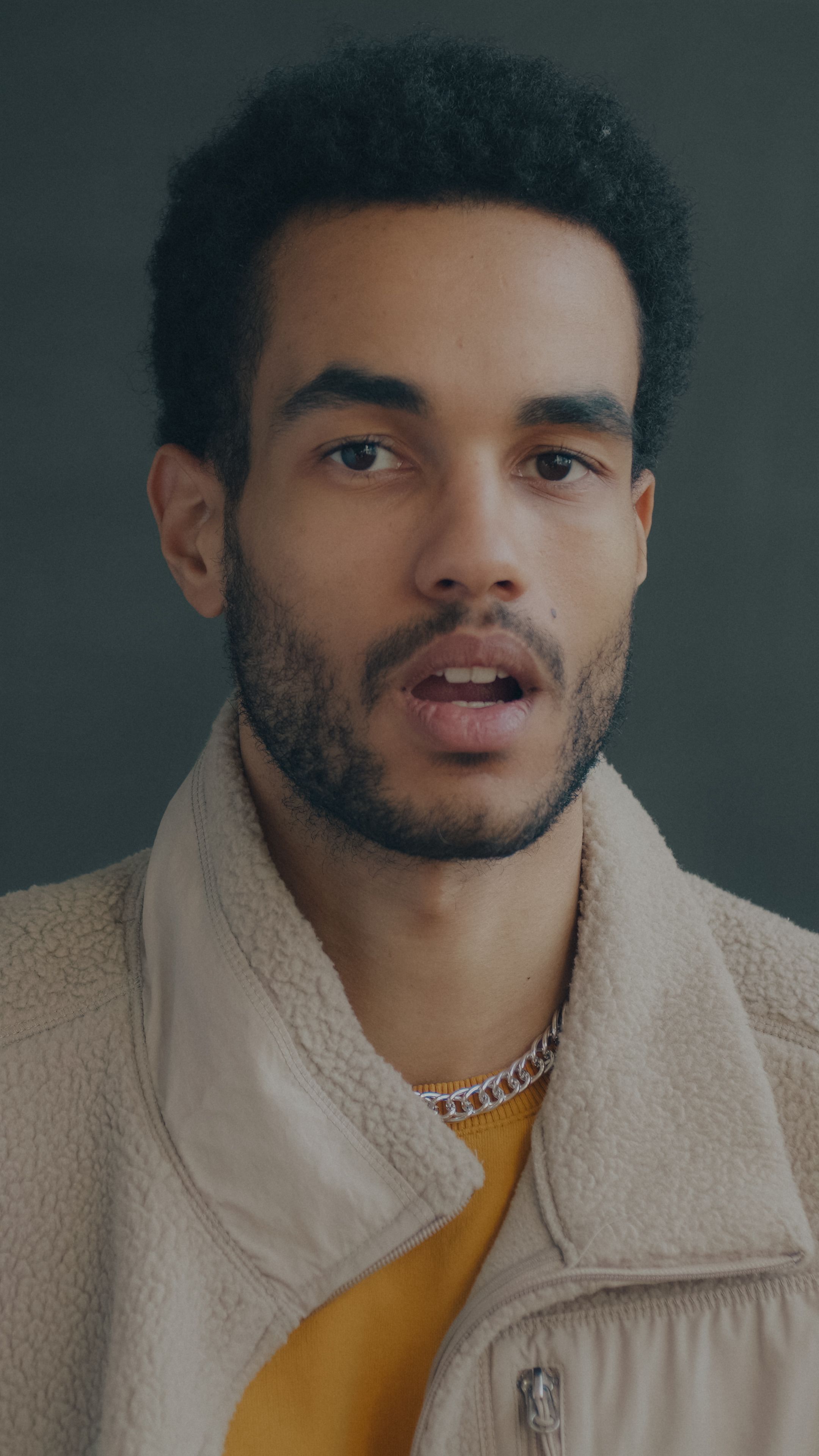 Close-up portrait of a young man with a neutral expression, wearing a fleece jacket.