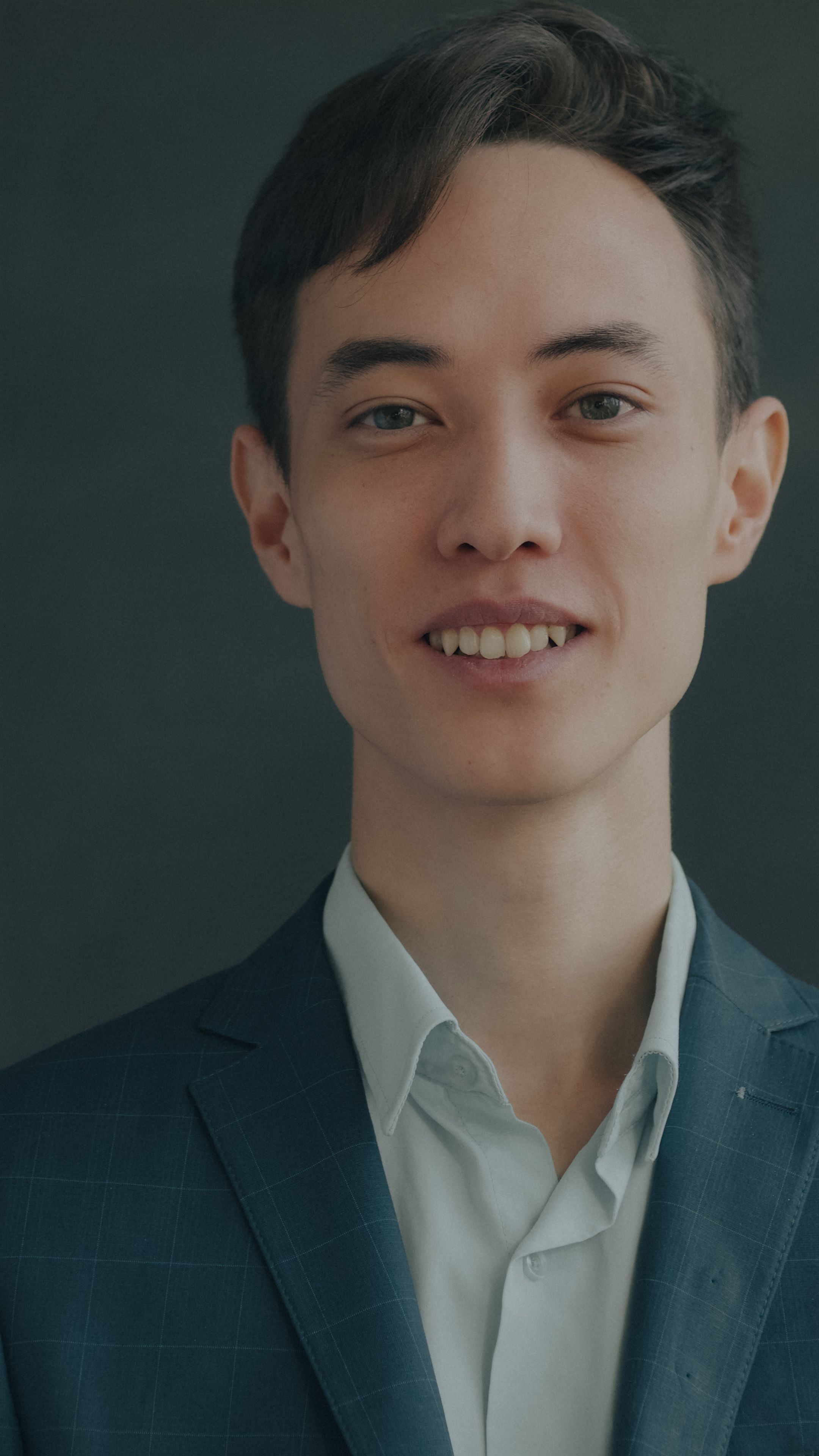 Confident young adult male in a suit, posing in a studio.