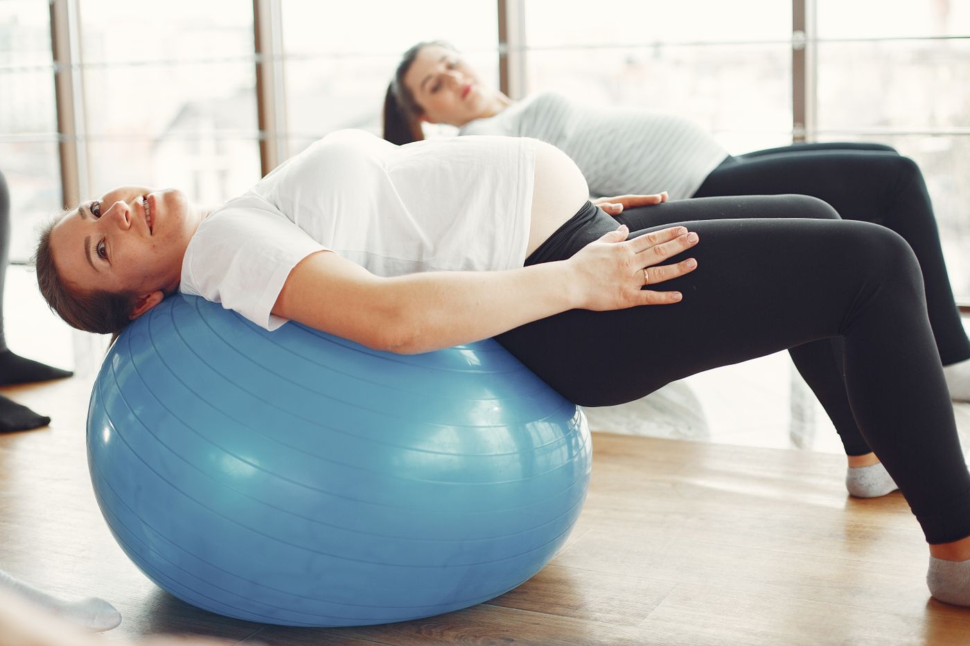 Future maman habillée d’un tee-shirt blanc utilisant un ballon de grossesse
