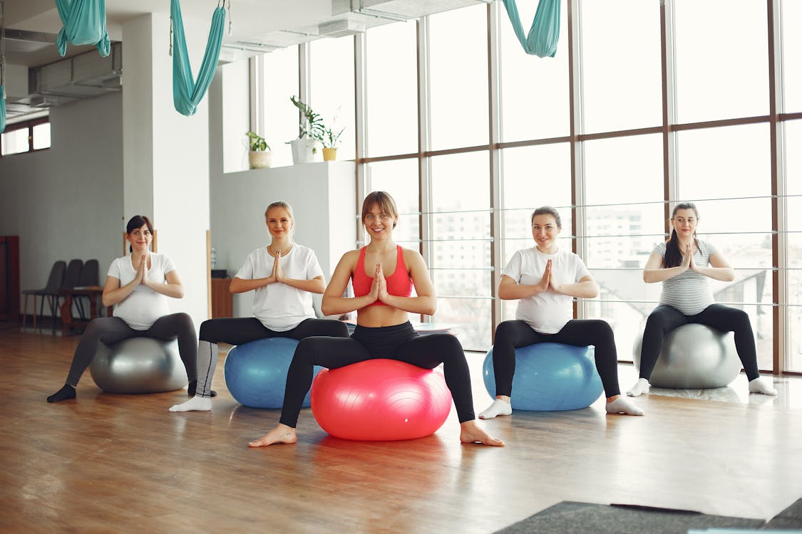 Group of people on yoga balls with instructor in the middle.