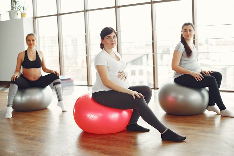 Content Young Pregnant Women During Fitness Workout In Modern Studio