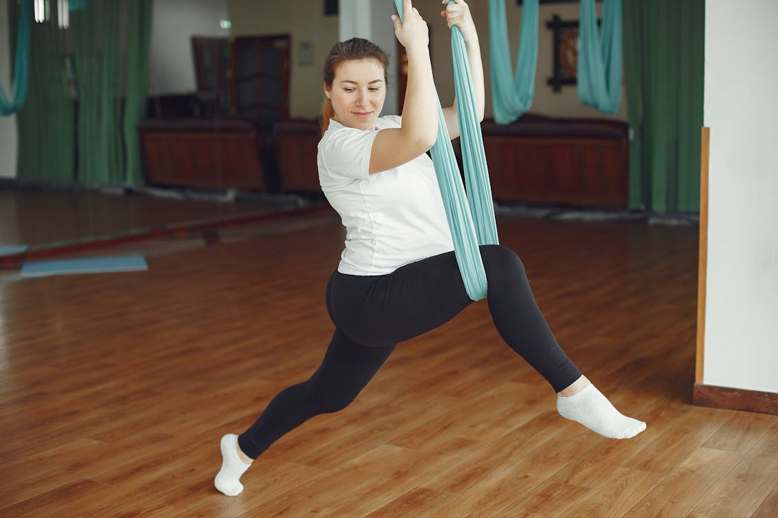 Young pregnant woman during exercise of aerial yoga
