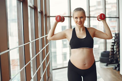 Woman in Black Sports Bra and Black Shorts Holding Red Kettle Bell