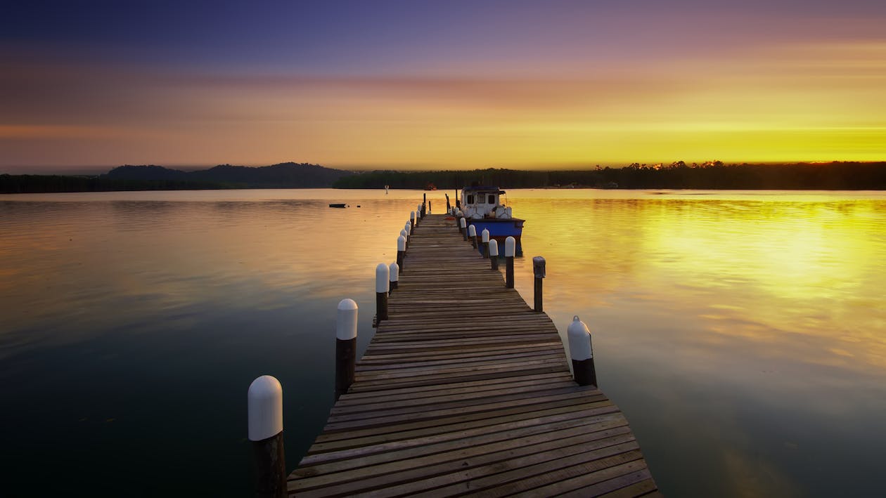 Witte Jacht Naast Bruin Houten Dok Op Waterlichaam Tijdens Zonsondergang