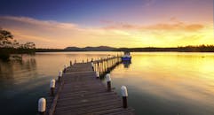 在乡村码头延伸至湖中的平静水面上，欣赏令人惊叹的日落景色