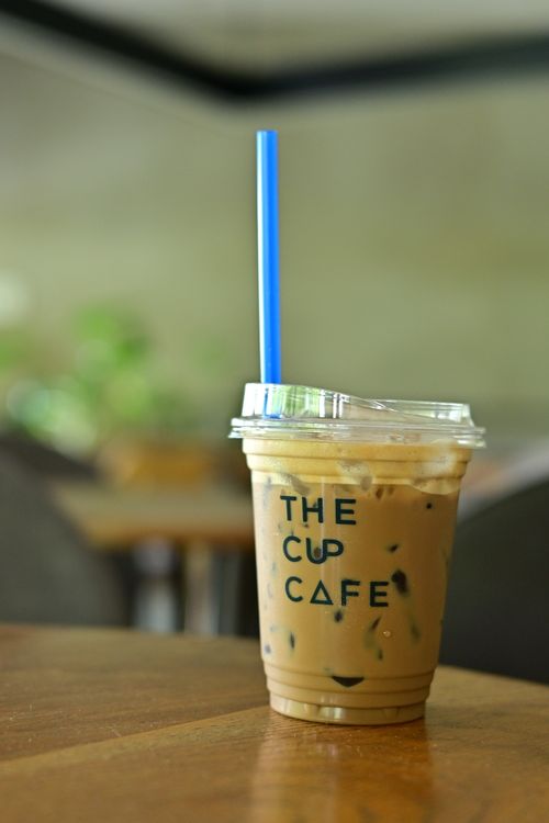 Free Close-up of iced coffee in a plastic cup with blue straw at The Cup Cafe. Stock Photo