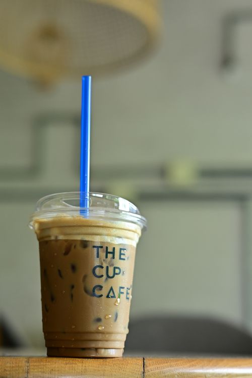 Free Refreshing iced coffee with a blue straw at The Cup Cafe, perfect for a summer day. Stock Photo