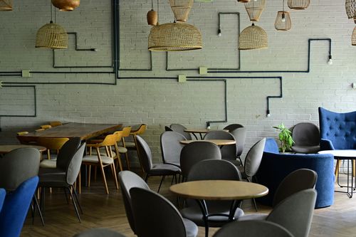 Free Cozy and modern cafe interior featuring wicker lamps, diverse seating, and a minimalist aesthetic. Stock Photo