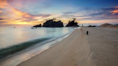 海滩上，日落景色宁静，船只在旁，天空充满活力