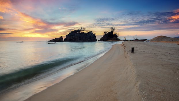 海滩上，日落景色宁静，船只在旁，天空充满活力