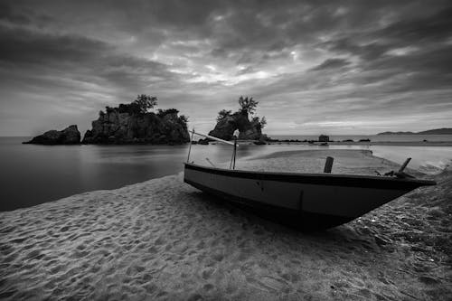 Gray Scale Photography of Brown Boat on Seashore