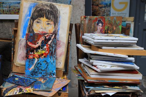 Free Stacked paintings at an art gallery in Limone Sul Garda, Italy. Vibrant colors and portraits capture artistic spirit. Stock Photo