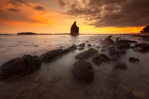 Rock Formations on Body of Water during Sunset