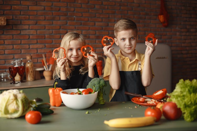 Children In The Kitchen Holding Slices Of Capsicum