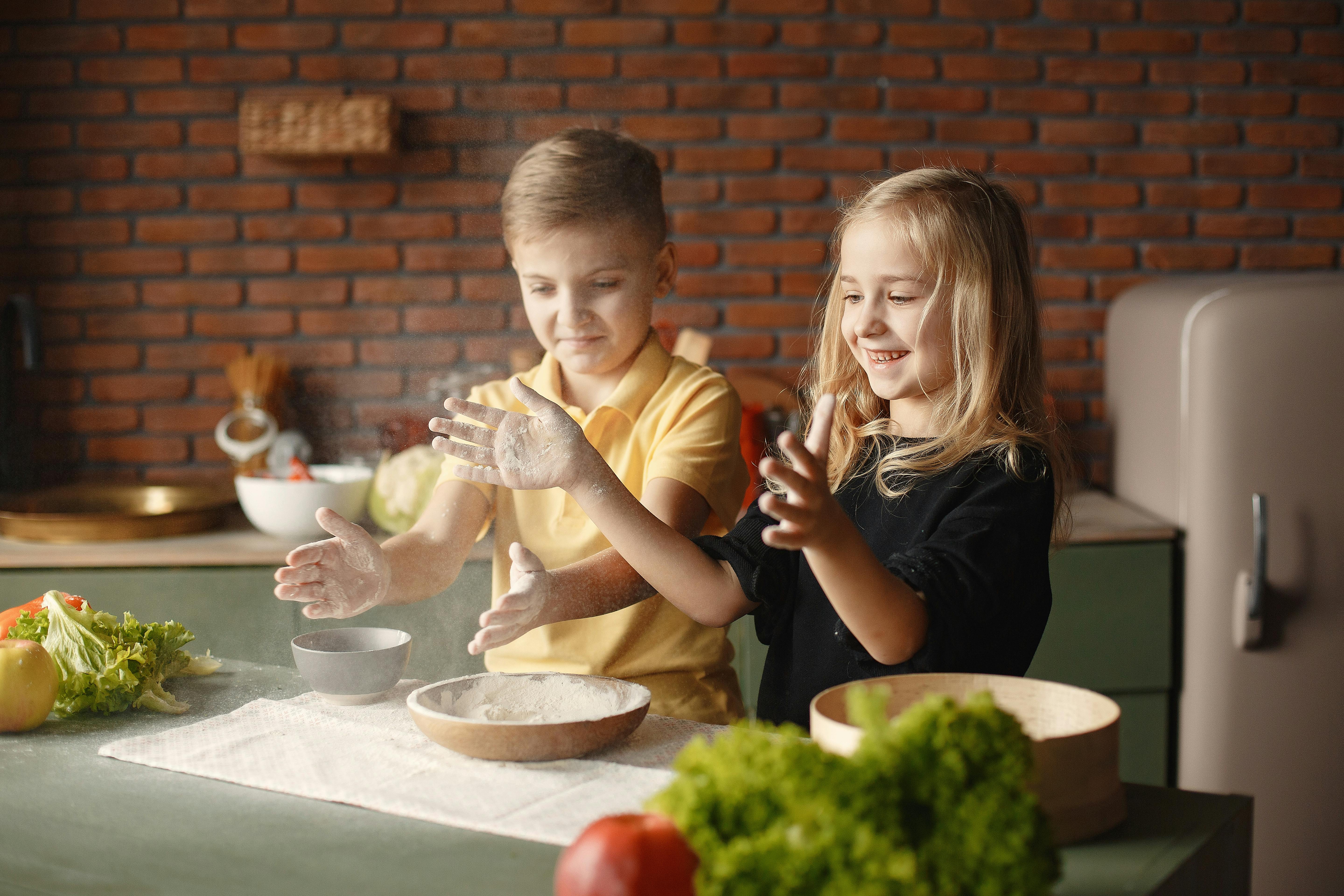 happy children putting flour on hands in kitchen in apartment