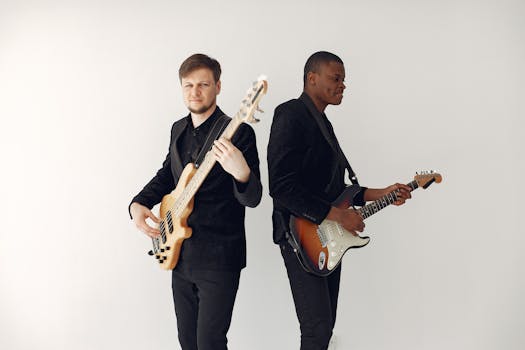 Two musicians playing electric guitars in studio, showcasing fashion and musical talent.