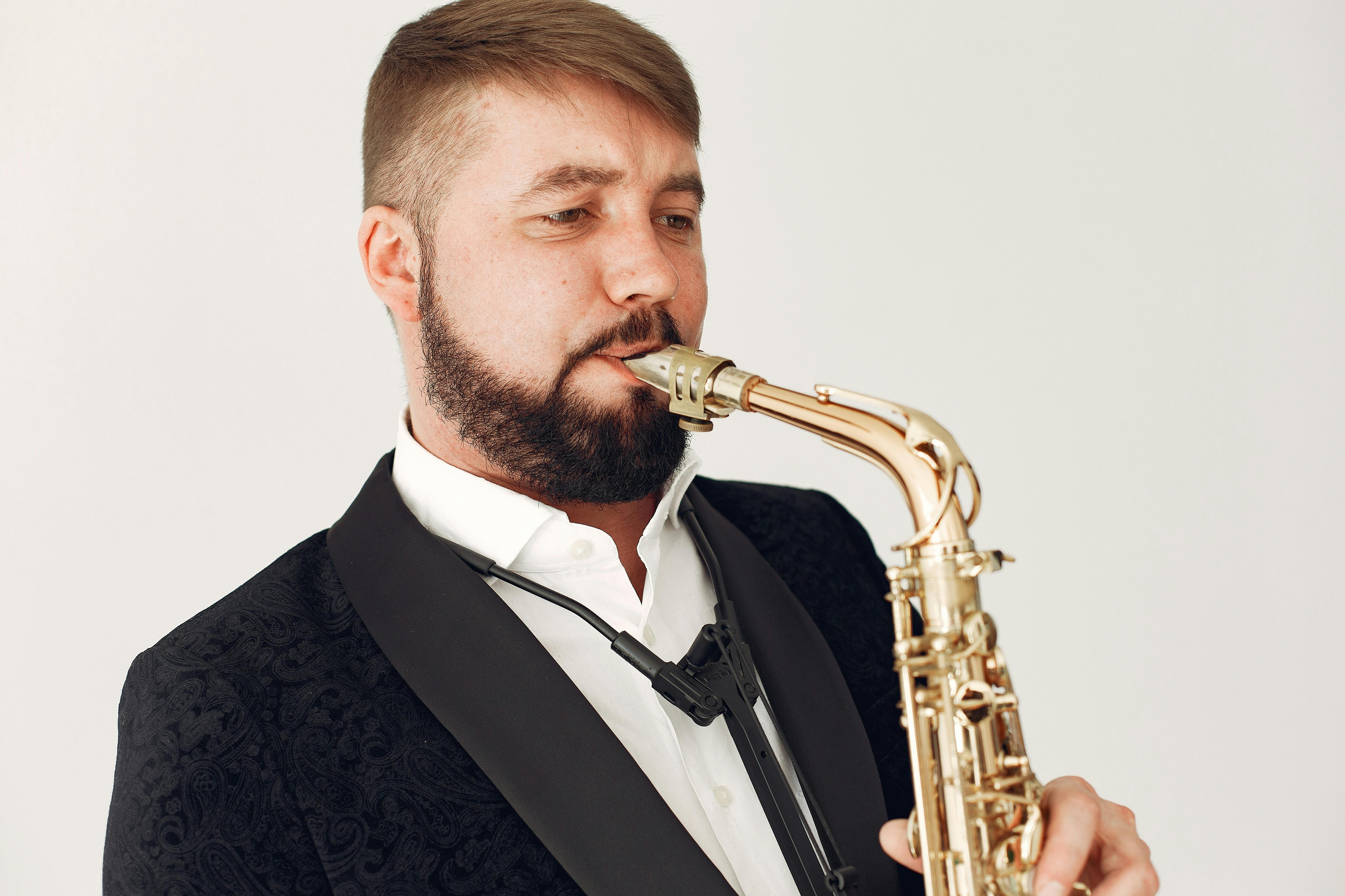 man in black suit jacket playing saxophone