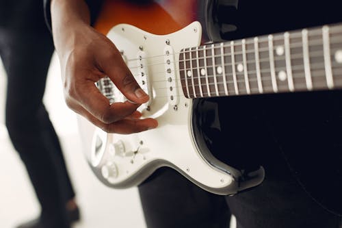 Free Unrecognizable young male musician playing electric guitar while standing near anonymous colleague on blurred background during celebration party or live music show Stock Photo
