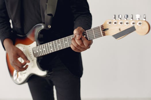 Close-up of a musician in a black suit playing an electric guitar indoors.
