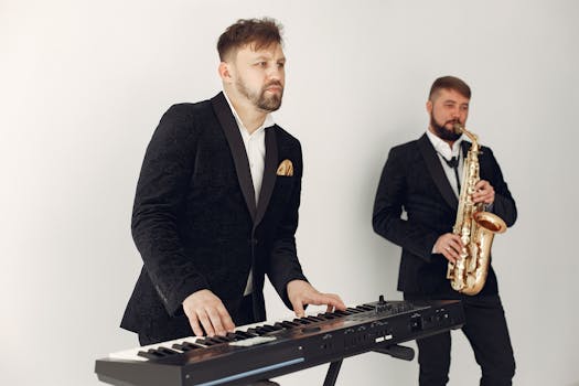 Two male musicians in suits playing a keyboard and saxophone in a studio setting.