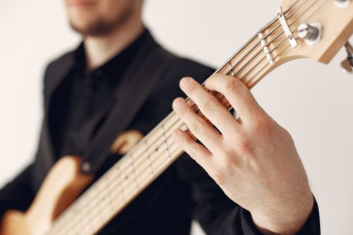 Free Musician playing bass guitar in a studio setting, focusing on hands and strings. Stock Photo