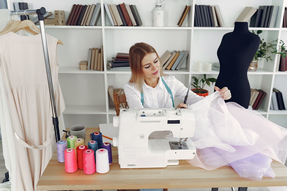 Woman in White Blouse Sitting on Chair in Front of Sewing Machine