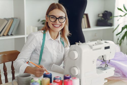 Free Dressmaker in front of her Sewing Machine Smiling Stock Photo