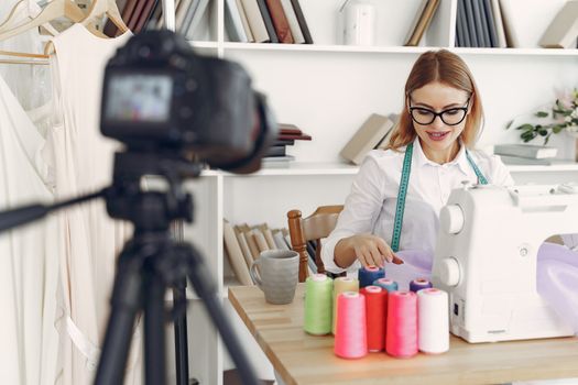 Female designer working at sewing machine with colorful threads in a modern studio.