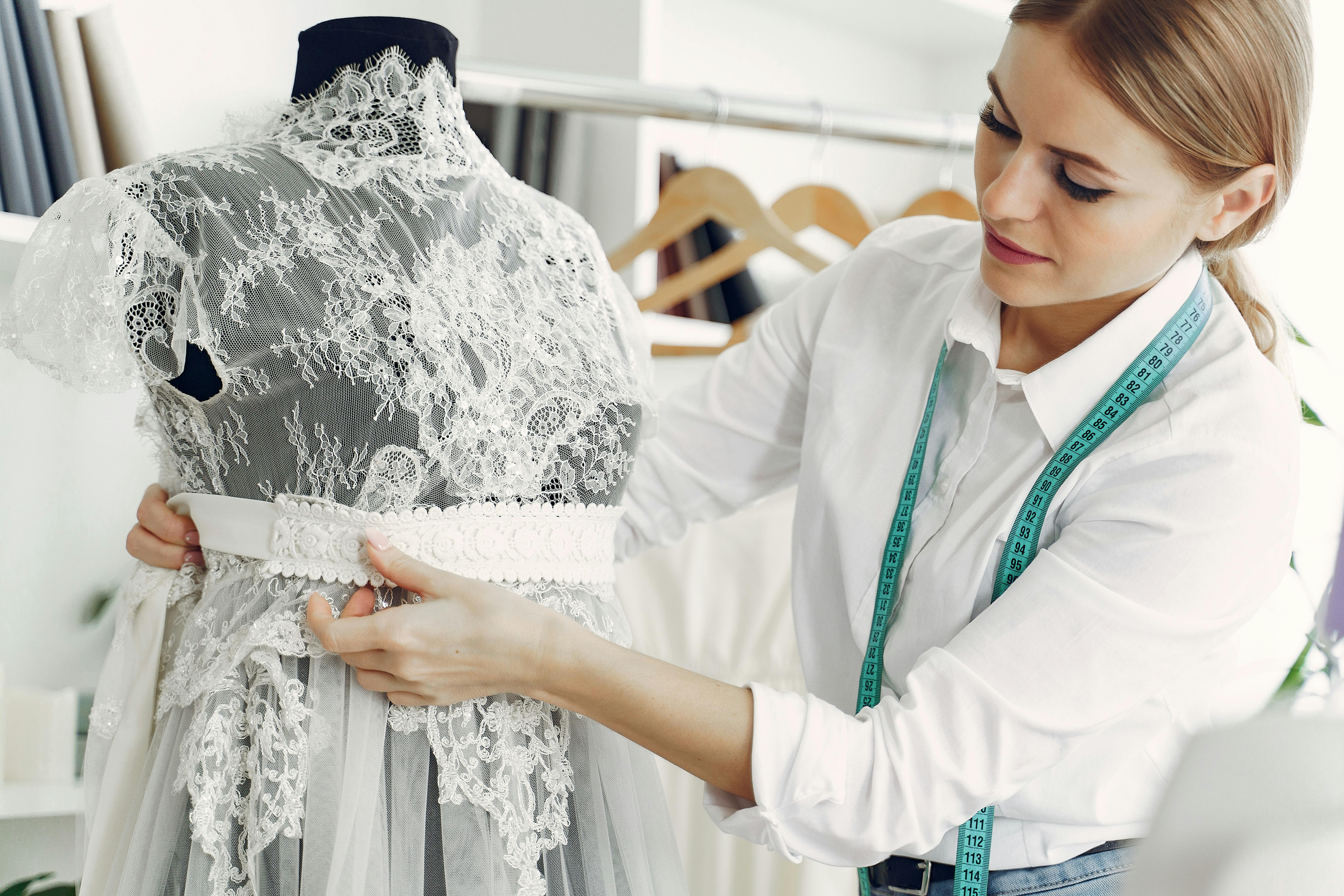 focused female dressmaker creating wedding dress in workshop