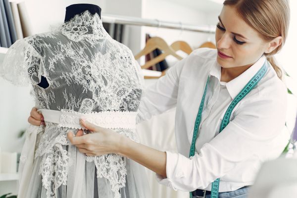 A sash being pinned onto a lace gown on the stand