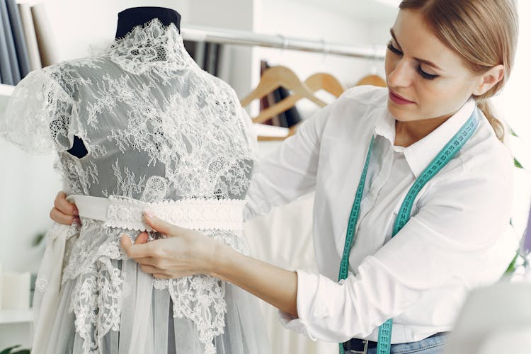 Focused Female Dressmaker Creating Wedding Dress In Workshop