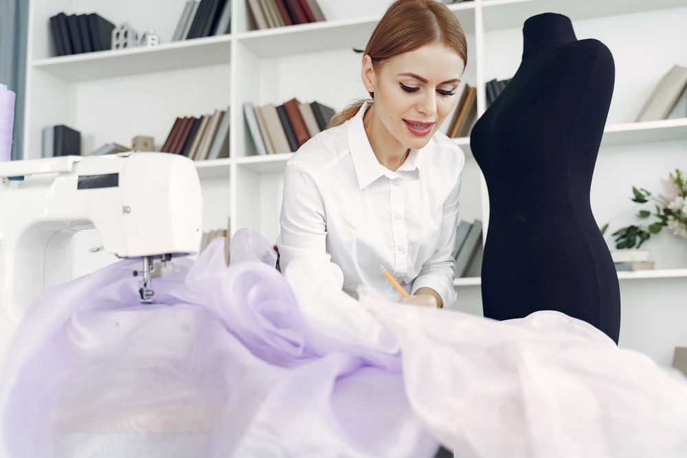 Designer smiling beside a lilac couture gown and dress form