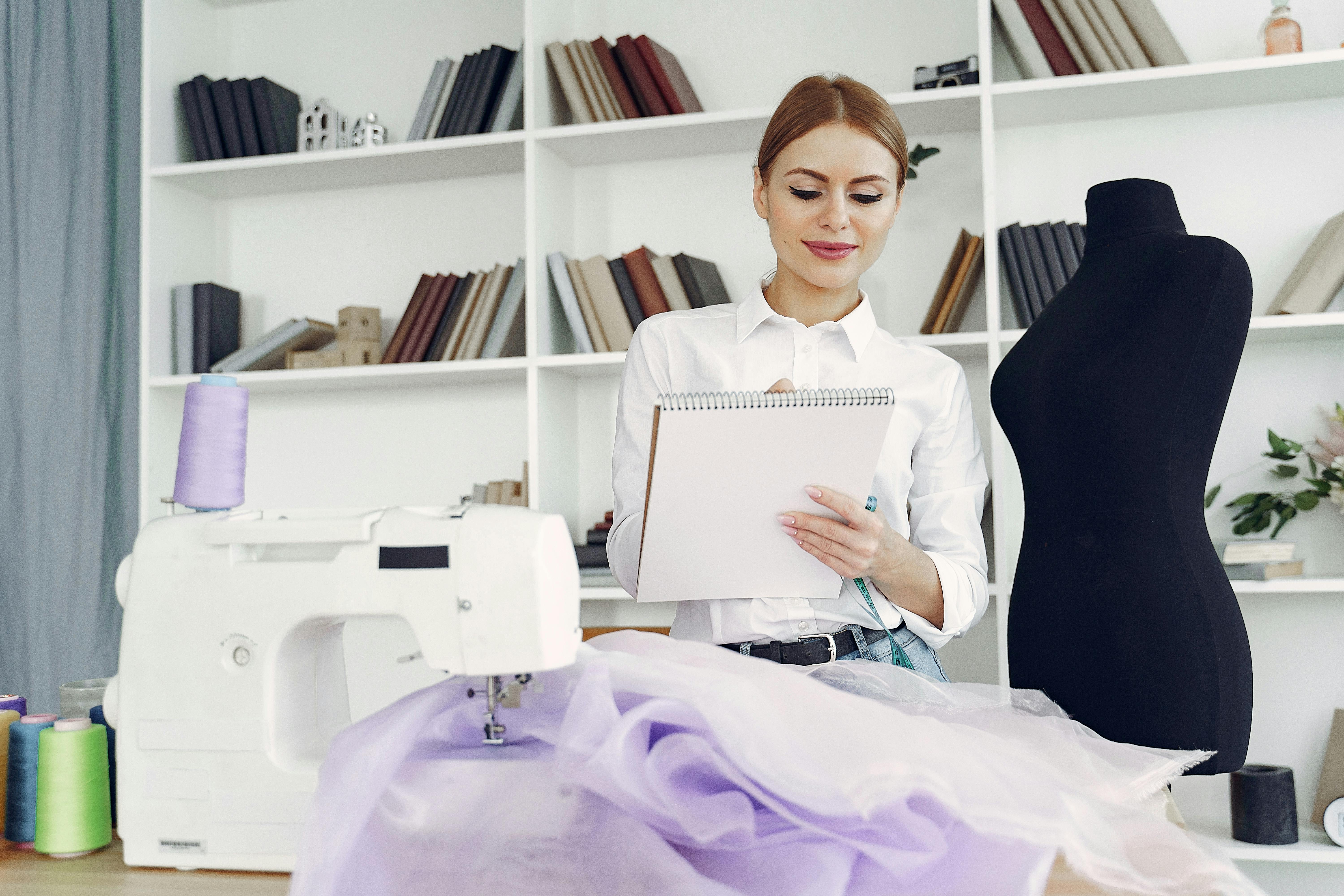 young positive female dressmaker creating party dress in tailor atelier