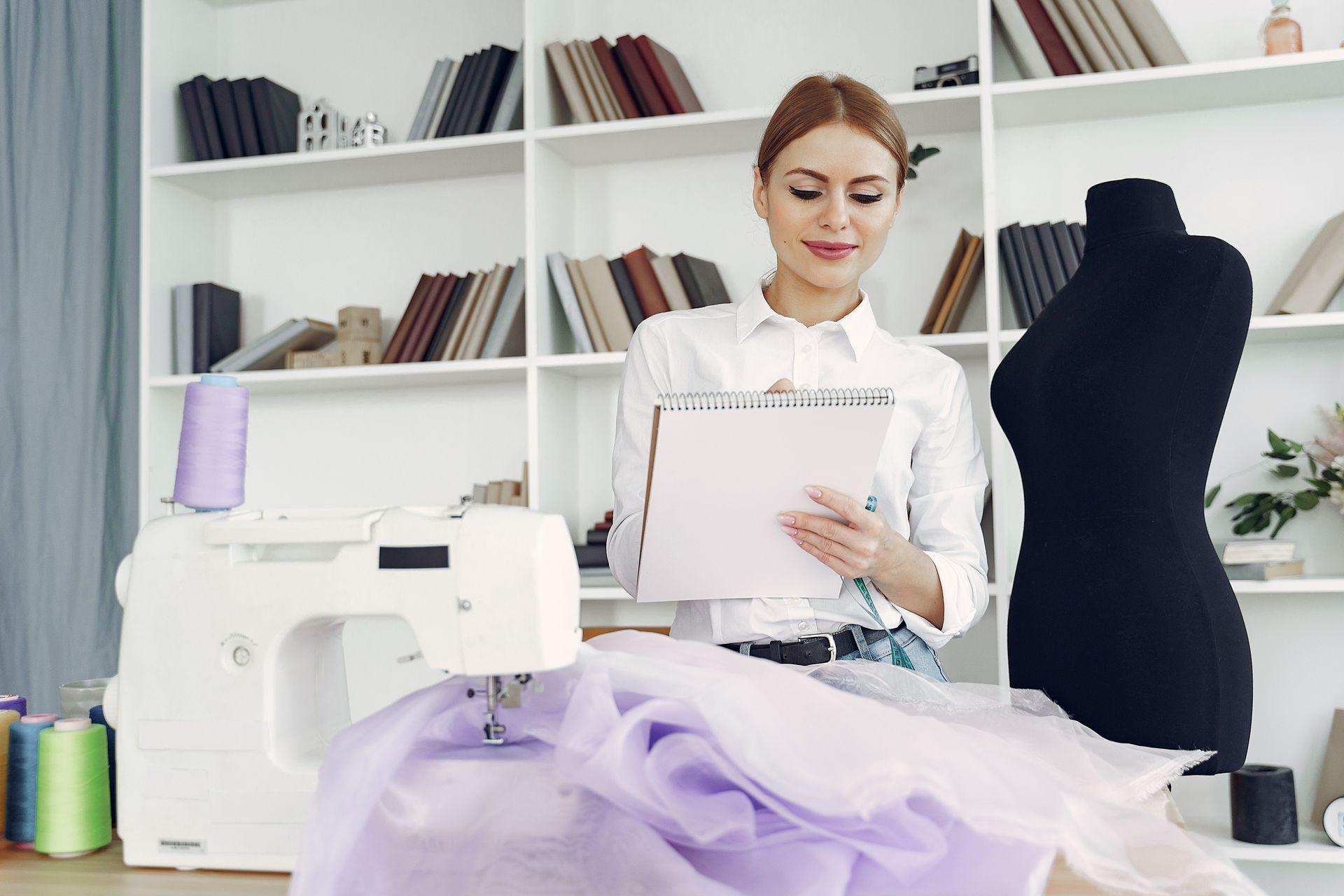 Young female fashion designer creating in her sewing studio with materials and mannequin.