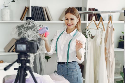 Smiling fashion designer records a sewing tutorial in her workshop studio.