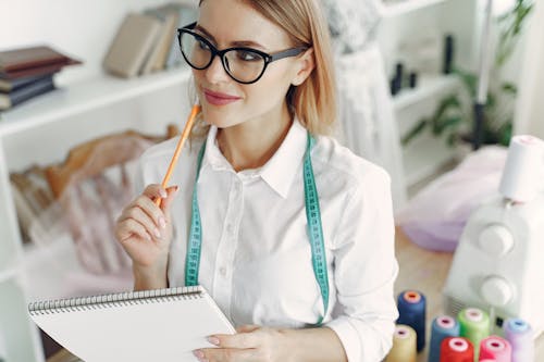 Woman in White Button Up Shirt Wearing Black Framed Eyeglasses Holding Sketchpad