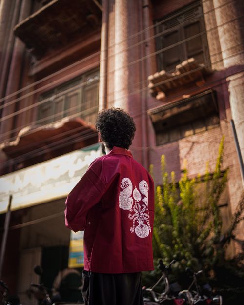 Free A man in a red jacket stands in front of a historic building in Pakistan. Stock Photo
