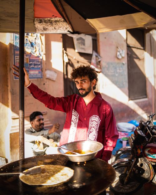 Free A street vendor in Pakistan prepares food in a bustling outdoor market. Stock Photo