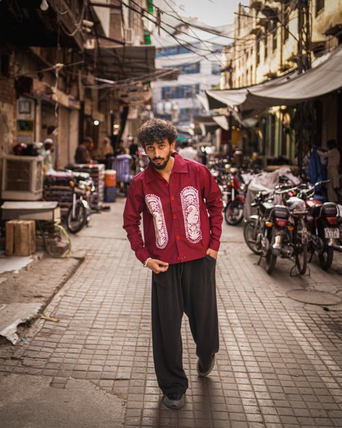 Free Fashionable man in a red shirt walks through a vibrant street in Lahore, Pakistan. Stock Photo