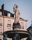 Old stone statue near building facade under blue sky