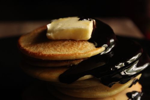 Free Close-up of stacked pancakes with butter and chocolate syrup for a tasty breakfast treat. Stock Photo