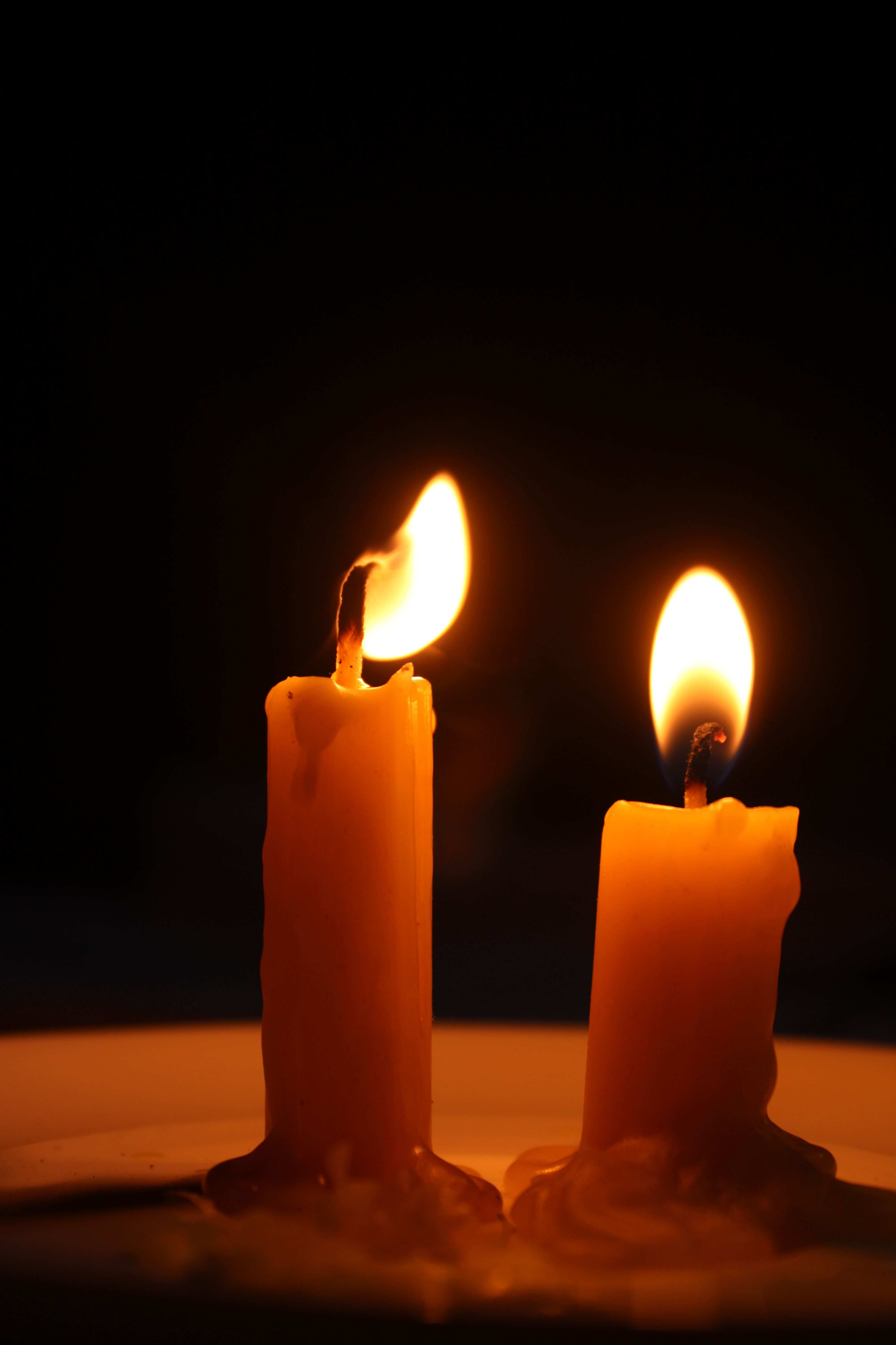 Two burning candles in the dark create a warm, serene atmosphere.