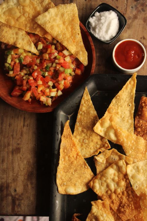 Free Top view of crispy nachos with fresh salsa, ketchup, and salt on a rustic table. Stock Photo