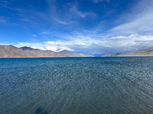 Free Stunning vista of Pangong Lake with clear blue waters and surrounding mountains under a vivid sky. Stock Photo
