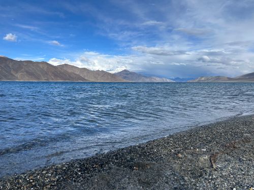 Free Vivid image of Pangong Lake with majestic mountains under a blue sky. Ideal for nature and travel enthusiasts. Stock Photo
