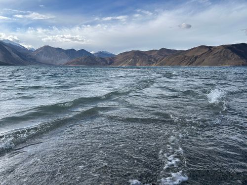 Free Breathtaking view of Pangong Lake with rippling water and majestic mountains under a clear sky. Stock Photo