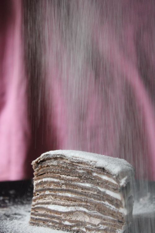 Free Close-up of a layered chocolate cake with powdered sugar falling, creating a sweet treat visual. Stock Photo